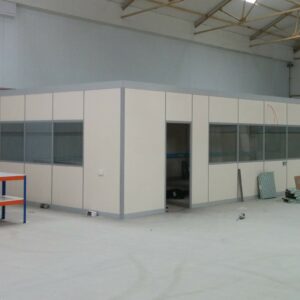 Half glazed demountable warehouse office partition in Herefordshire. Grey aluminium framework, and painted panels. Single glazed window modules.